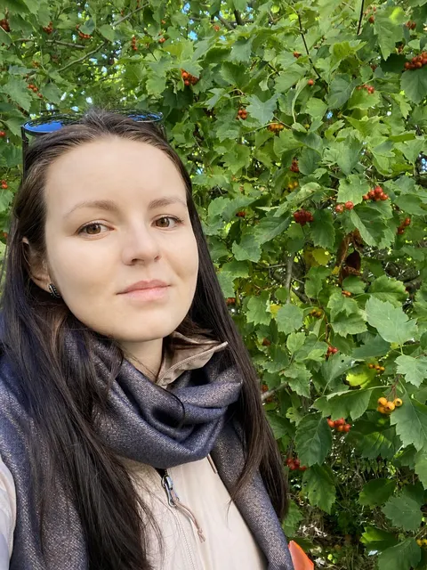 Anastasia outdoors beside green leaves